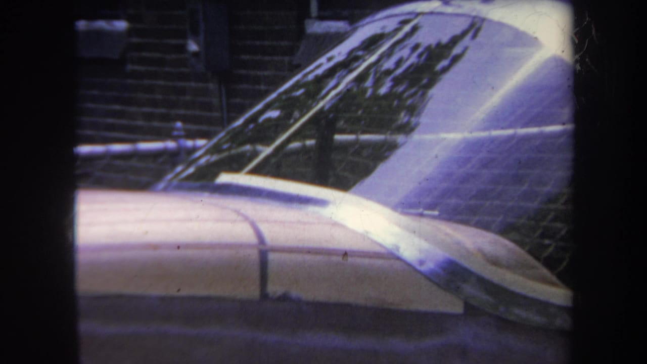 1969 Yucaipa home-movie frame showing a parked small aircraft fuselage and dome-like windshield with brickwork in the background.