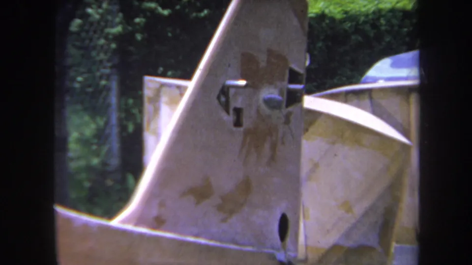 Final 1969 Yucaipa frame showing weathered industrial machinery with stained metal surfaces, hardware, a rounded form, and foliage.