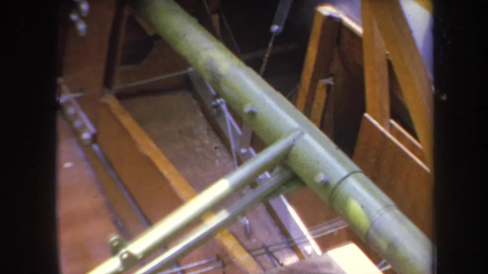 Close 1969 home-movie view of green tubular model aircraft components crossing over exposed wooden framing.