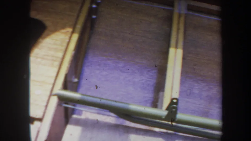 1969 Yucaipa home-movie view of curved wooden boat framing, pale interior strips, and a green metal brace across the lower edge.