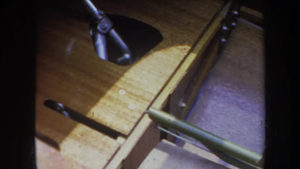 1969 Yucaipa frame showing a curved wooden boat section, green metal brace, rod hardware, and warm sunlight across the wood.
