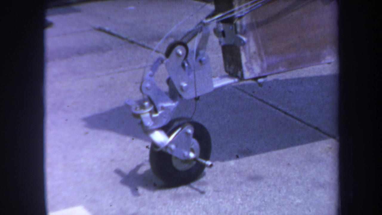 1969 Yucaipa 8mm frame showing a small wheel, metal bracket, hooks, and wooden beam on a concrete surface.