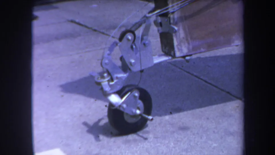 1969 Yucaipa 8mm frame showing a small wheel, metal bracket, hooks, and wooden beam on a concrete surface.
