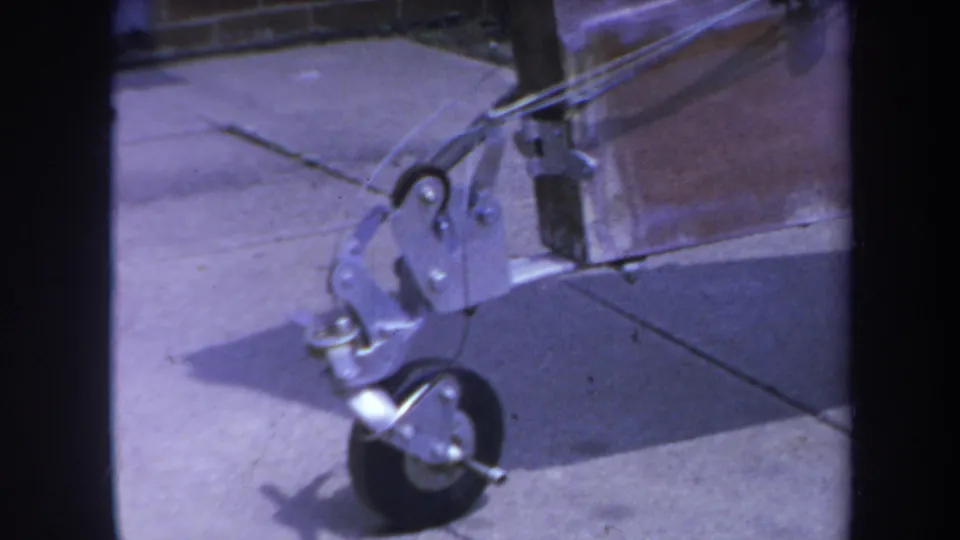 8mm frame from 1969 Yucaipa showing the wheeled metal support and attached hardware near a wood beam.