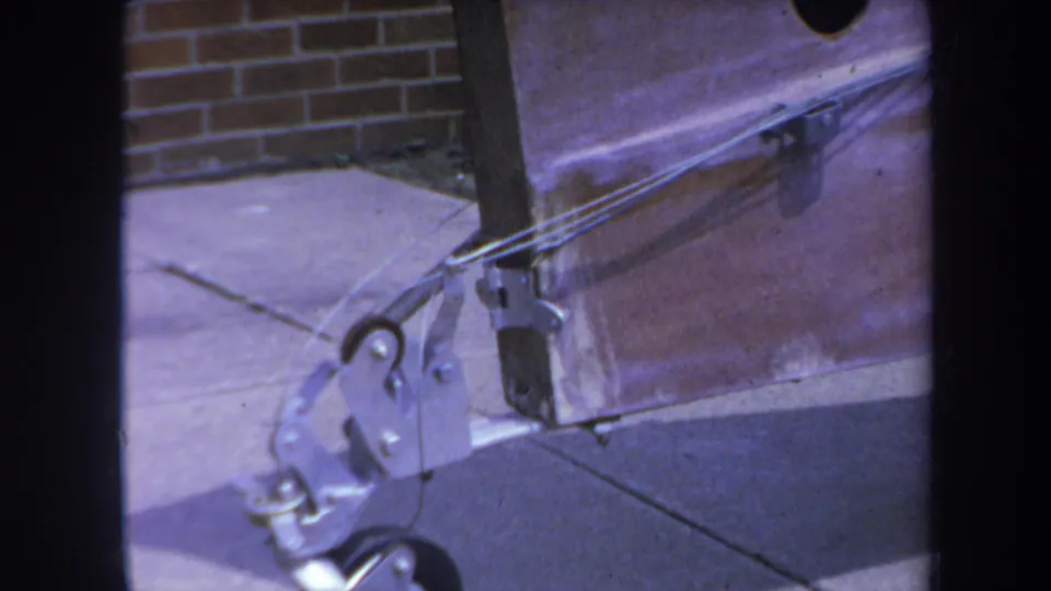 1969 Yucaipa frame showing the wheeled support assembly with a wood beam, concrete pad, and brick wall in the background.