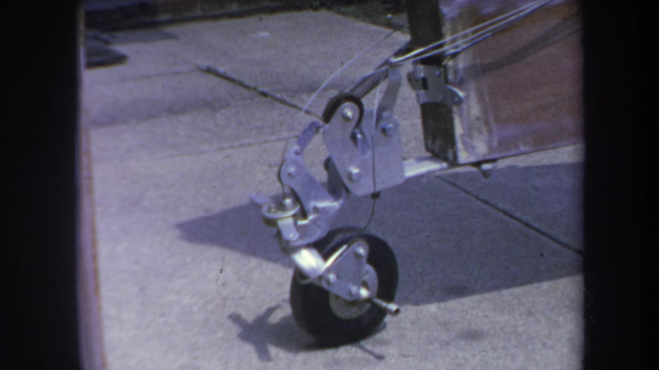 1969 Yucaipa 8mm frame showing the front caster wheel and metal bracket of a homemade trailer on a driveway.