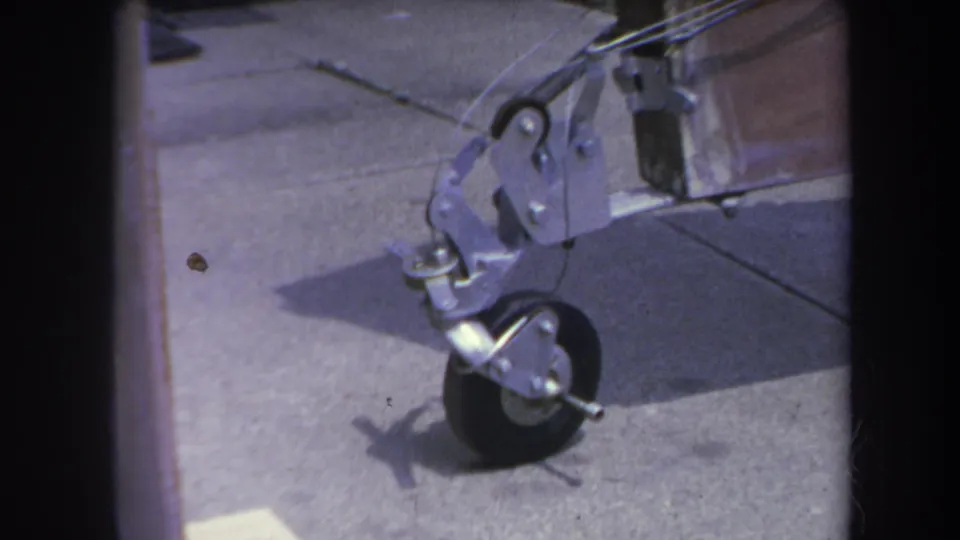 1969 Yucaipa frame showing the metal front wheel assembly of a homemade trailer, with driveway seams and shadows visible.