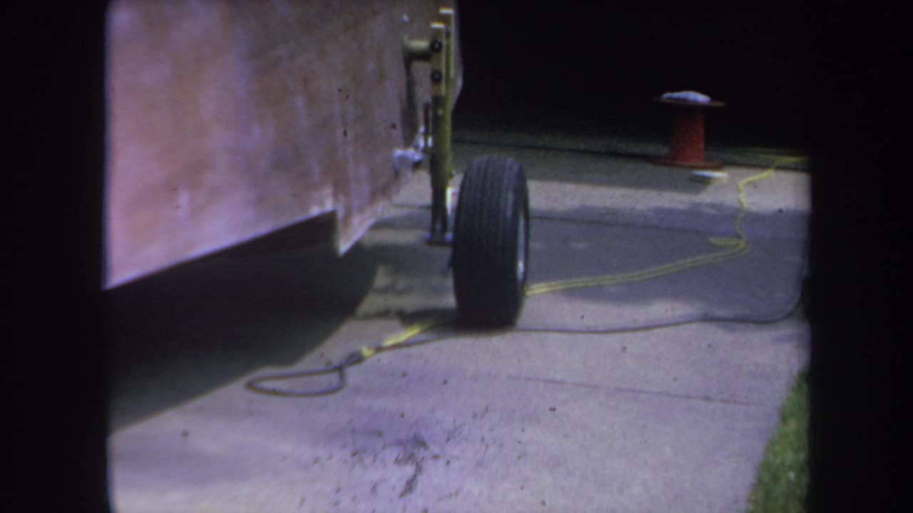 1969 Yucaipa-area 8mm frame showing a home-built trailer wheel beside a copper-toned side panel on a concrete driveway.