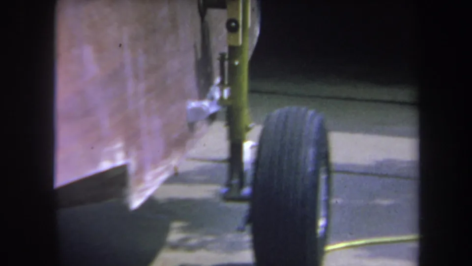 1969 home-movie closeup from Yucaipa showing the trailer wheel tucked beside painted axle hardware and a copper-toned panel.