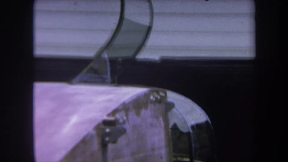 1969 Yucaipa-area frame showing the helicopter's worn fuselage and curved canopy near a white-sided house.