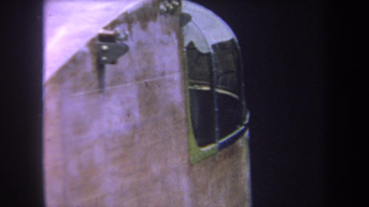Aircraft fuselage and cockpit window framed tightly with dark film edges.