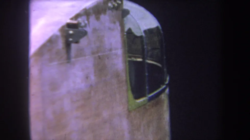 Tight 1969 8mm view of an aircraft cockpit window and curved fuselage surface, with visible grain and dark frame borders.