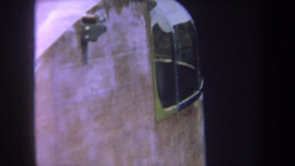 Close 8mm frame of the aircraft cockpit window and weathered fuselage, consistent with the 1969 Volmer Yucaipa metadata.