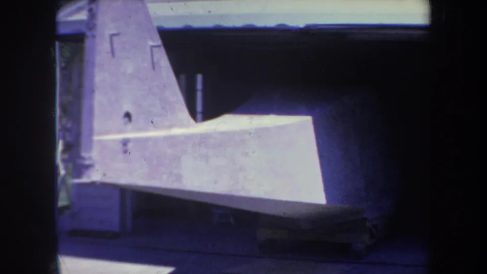 1969 Yucaipa-area 8mm frame showing a gray aircraft wing or tail assembly resting in shade beneath a shelter.