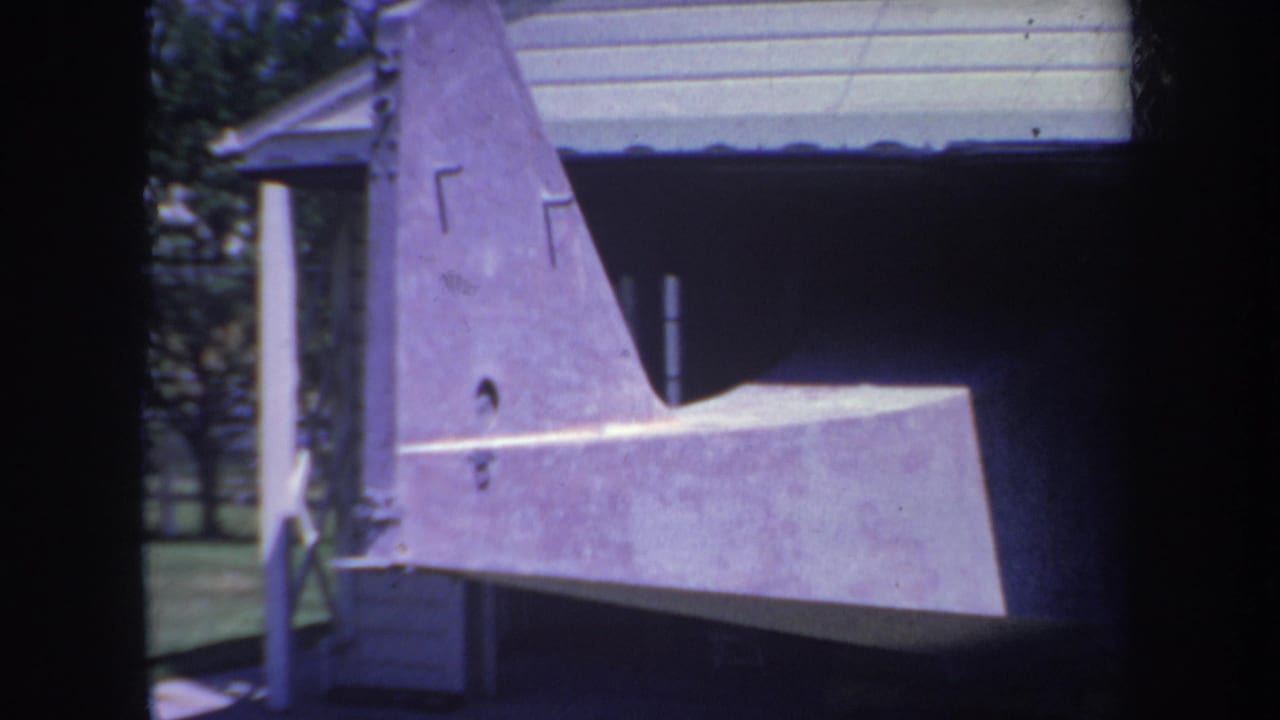 1969 Yucaipa home-movie frame showing a purple unfinished aircraft tail and stabilizer outside a garage.