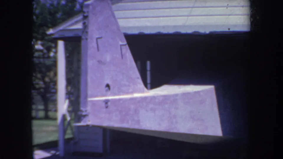 1969 Yucaipa home-movie frame showing a purple unfinished aircraft tail and stabilizer outside a garage.