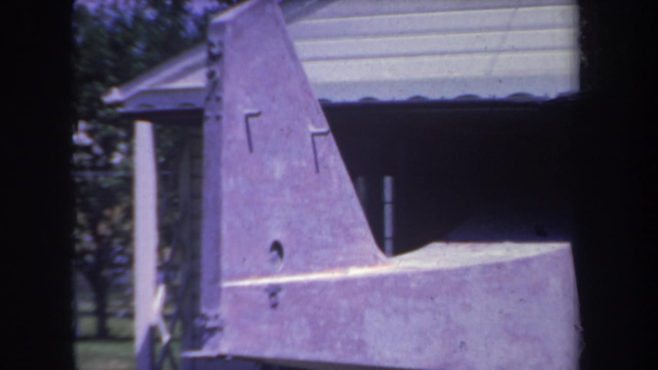 Aircraft tail fin and stabilizer in front of a garage opening.