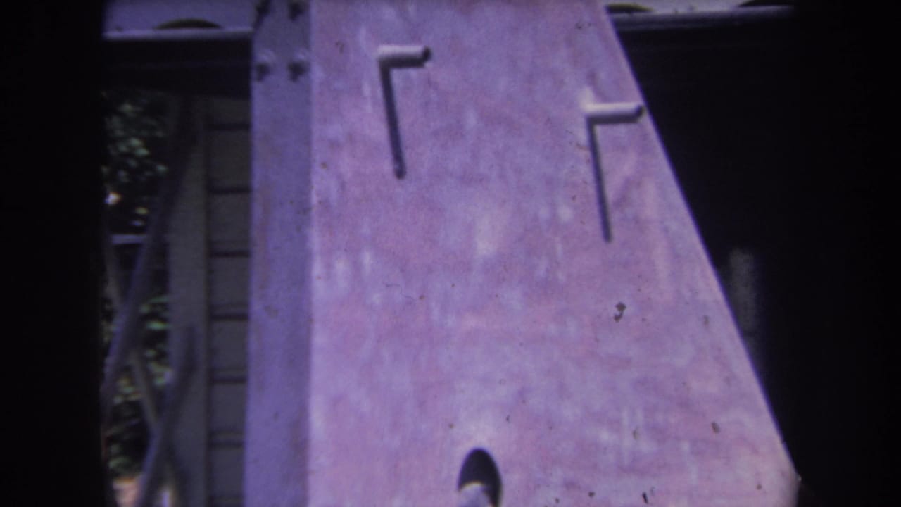 1969 8mm frame from Yucaipa showing a close view of a purple-tinted metal sculpture surface with rivets and dark borders.