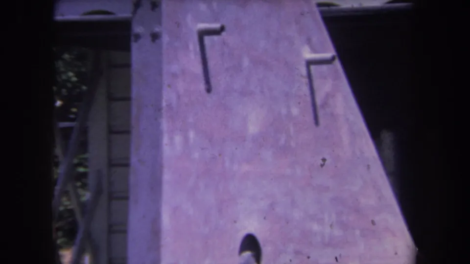 1969 8mm frame from Yucaipa showing a close view of a purple-tinted metal sculpture surface with rivets and dark borders.