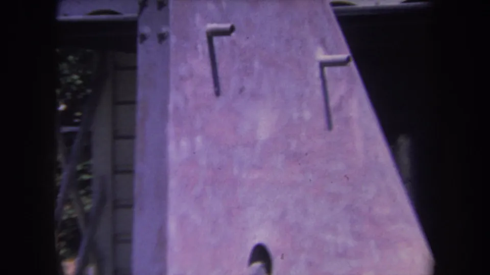 1969 Yucaipa home-movie frame showing the metal sculpture panel in close-up, with rivets and a dark edge at right.
