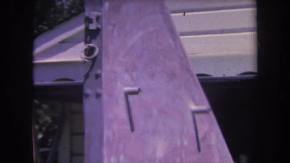 1969 Yucaipa frame showing an angled portion of the outdoor metal sculpture against pale siding and greenery.