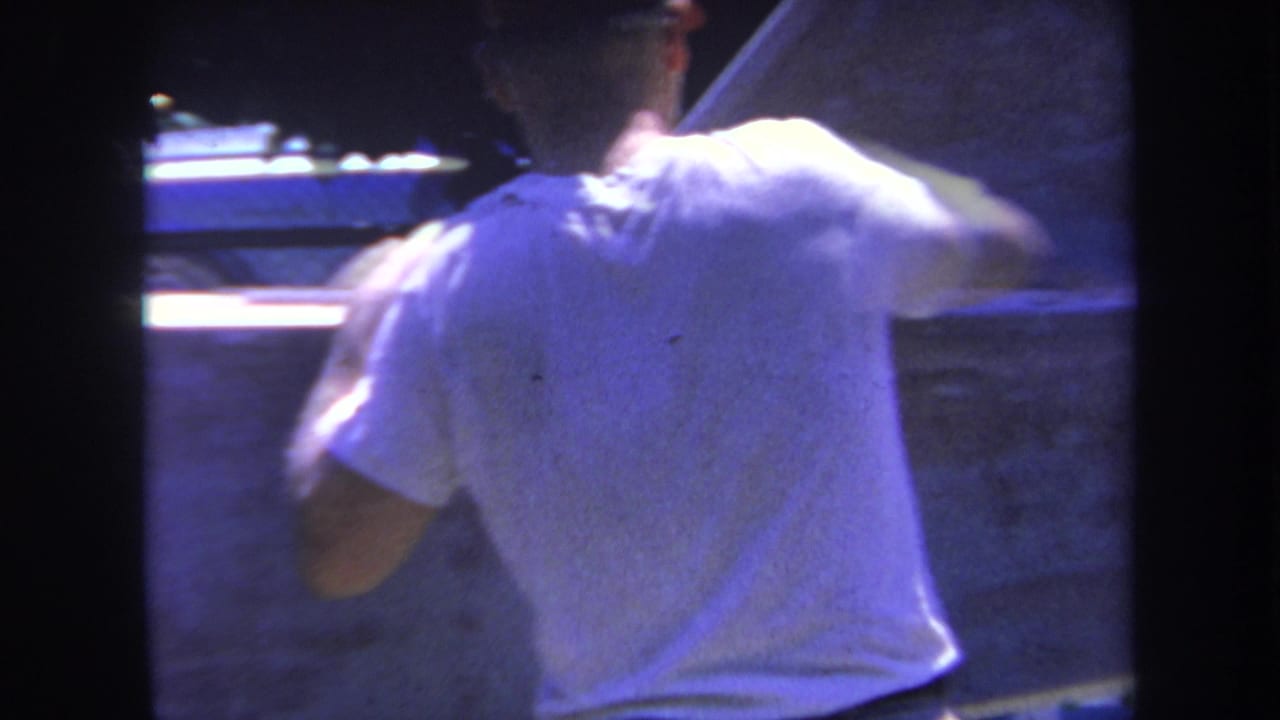 In 1969 Yucaipa-area 8mm footage, a man in a white T-shirt and cap appears to work on a large pale aircraft or vehicle surface.