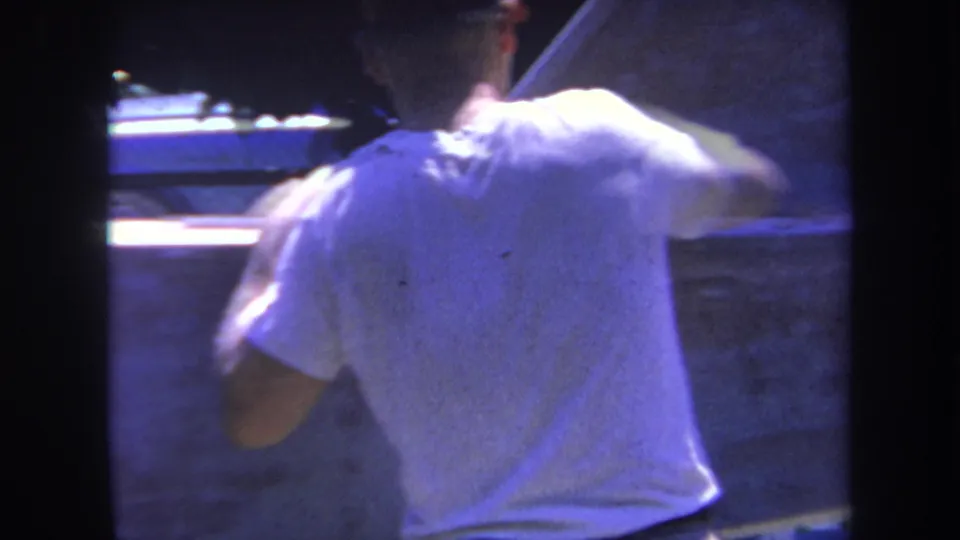 In 1969 Yucaipa-area 8mm footage, a man in a white T-shirt and cap appears to work on a large pale aircraft or vehicle surface.