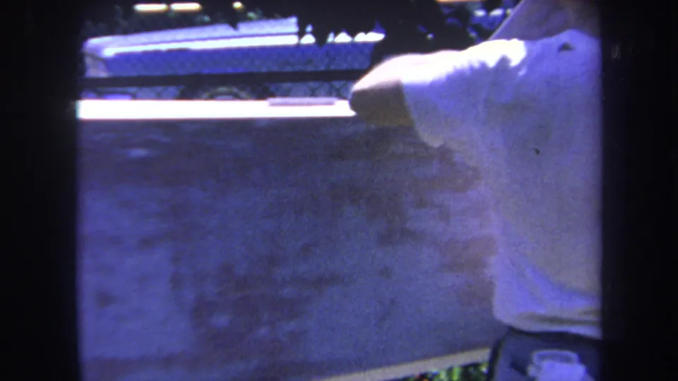 The man remains close to the large surface, partly cut off by the contact-sheet frame, with fence detail and strong blue cast visible.