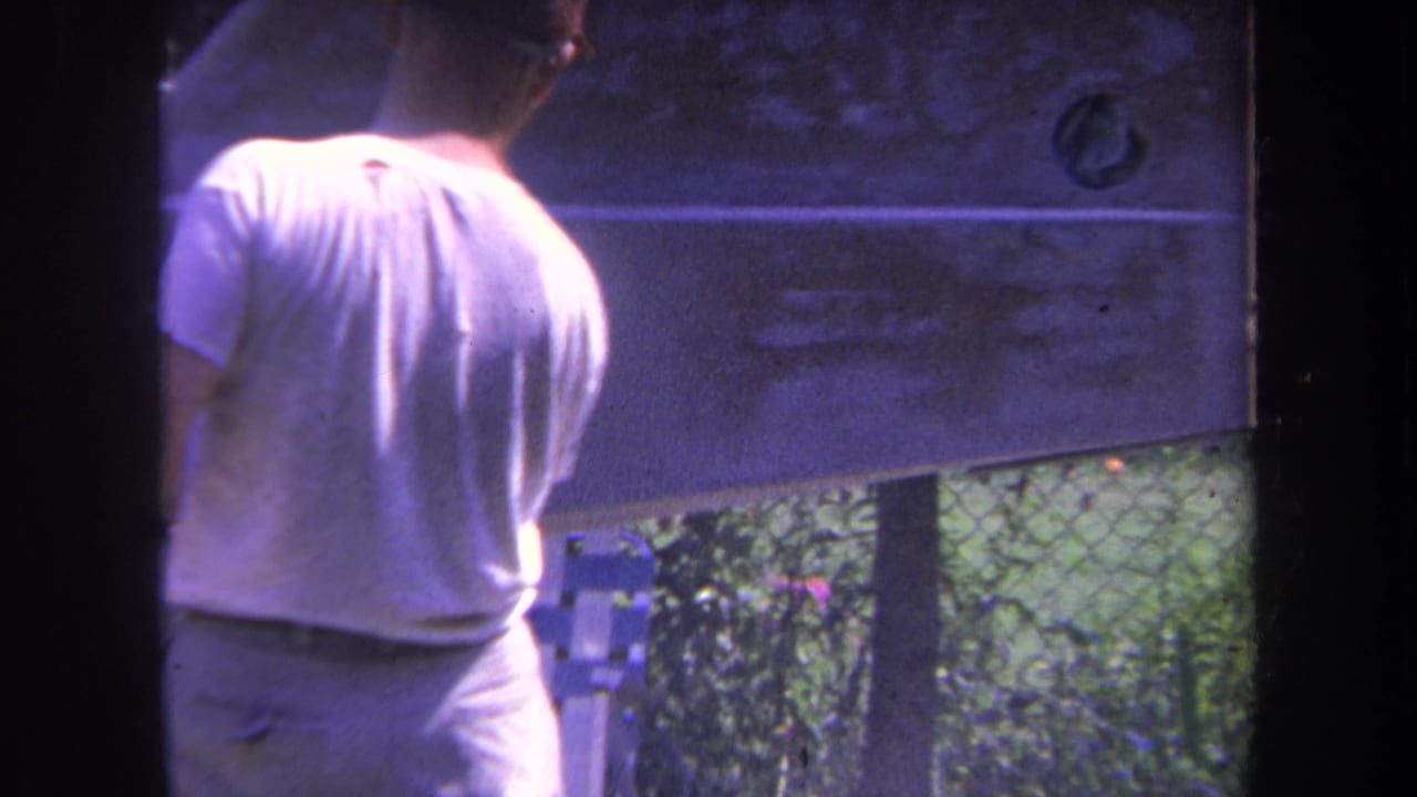 Man seen from behind beside a small aircraft tail section outdoors.