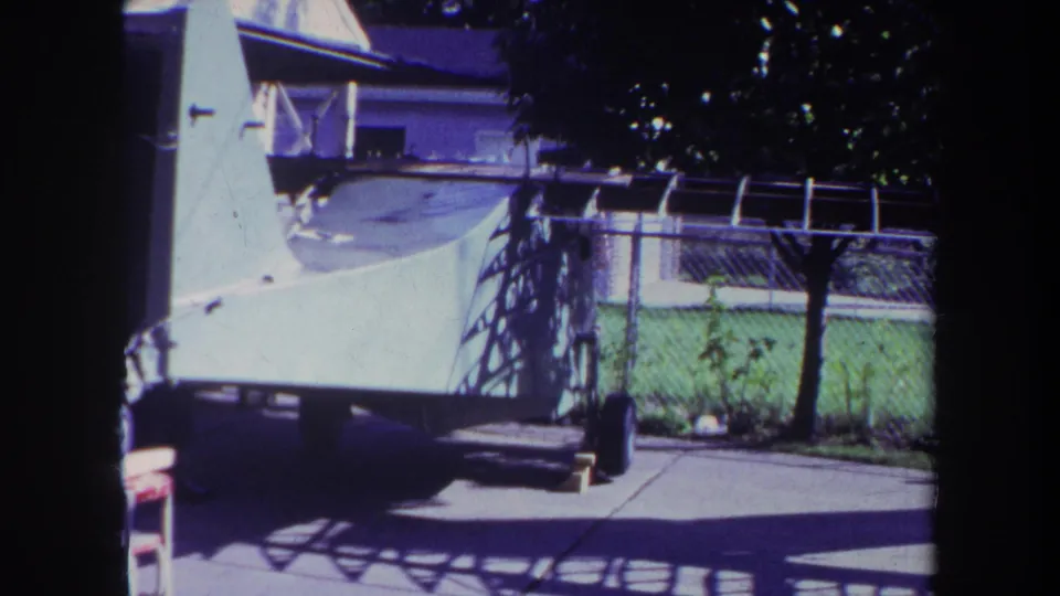 Final 1969 Yucaipa frame of the small white aircraft on its trailer in a bright residential driveway setting.