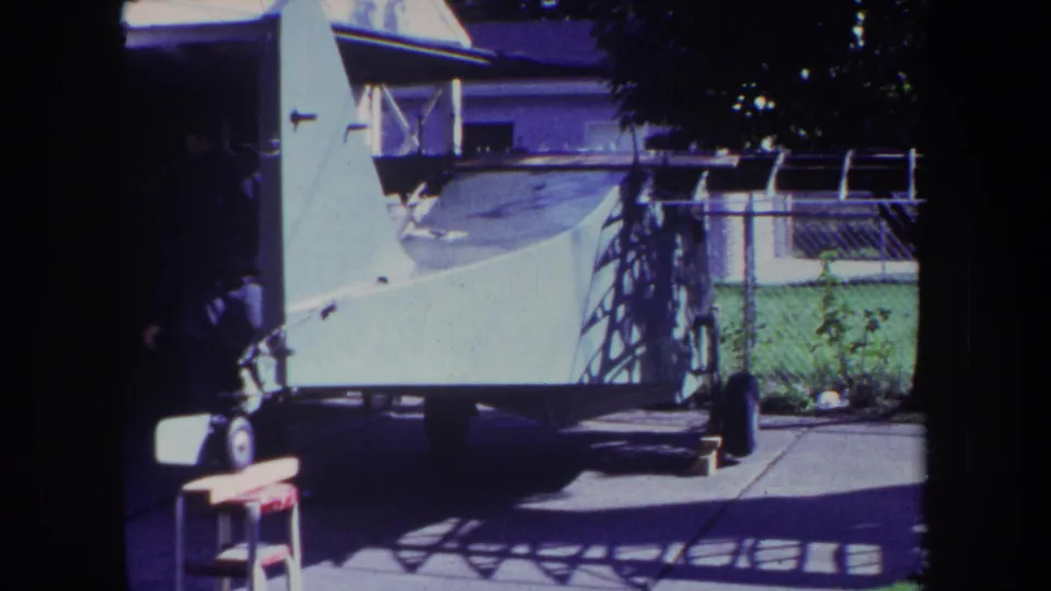 1969 Yucaipa frame showing a residential backyard patio with a white trailer-mounted watercraft, fence, covered pool area, and house exterior.