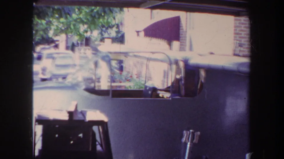 1969 Yucaipa garage view of a home-built airplane, with its windshield and upper surface visible against a brick house and awning.
