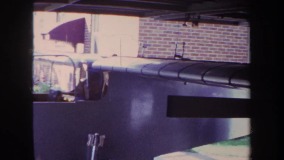 Final 1969 Yucaipa frame holds on the home-built aircraft in the garage, with residential brickwork and striped awning visible beyond.