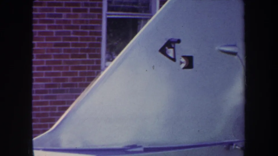1969 Yucaipa-area 8mm frame showing the ramp face with small dark stickers or markings, backed by a brick wall and window.