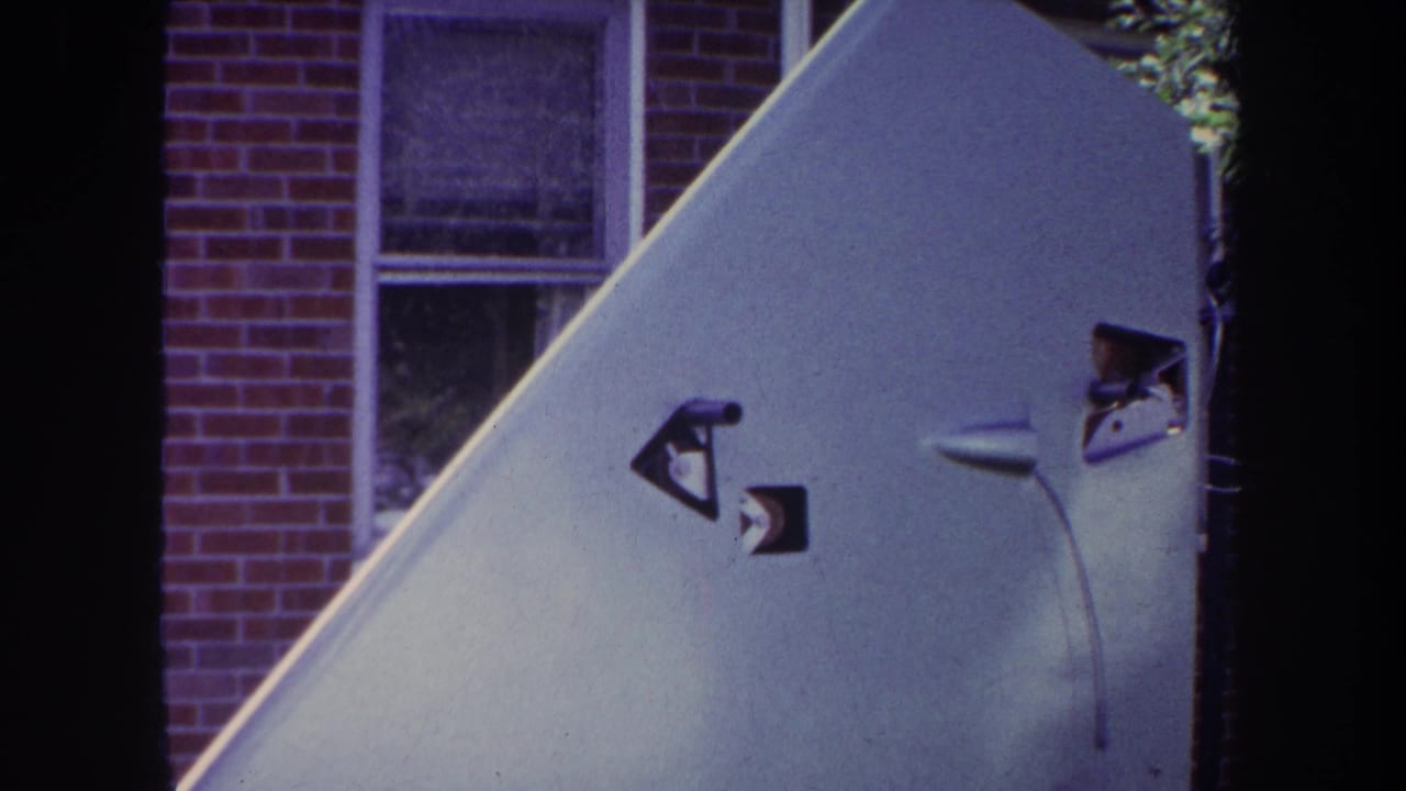 Close view of a pale aircraft tail fin beside a brick house and window.