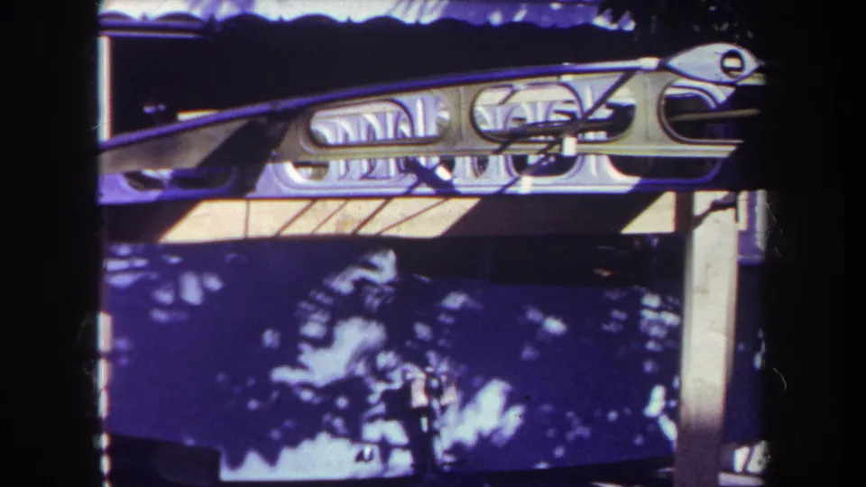 1969 Yucaipa fairground detail showing decorative metalwork, booth surfaces, and strong sunlight shadows as the camera pans away.