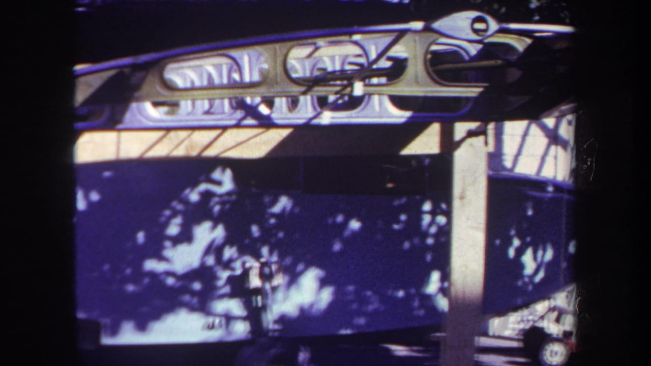 Close view of a dark boat hull under a pale metal frame with tree-shadow reflections.