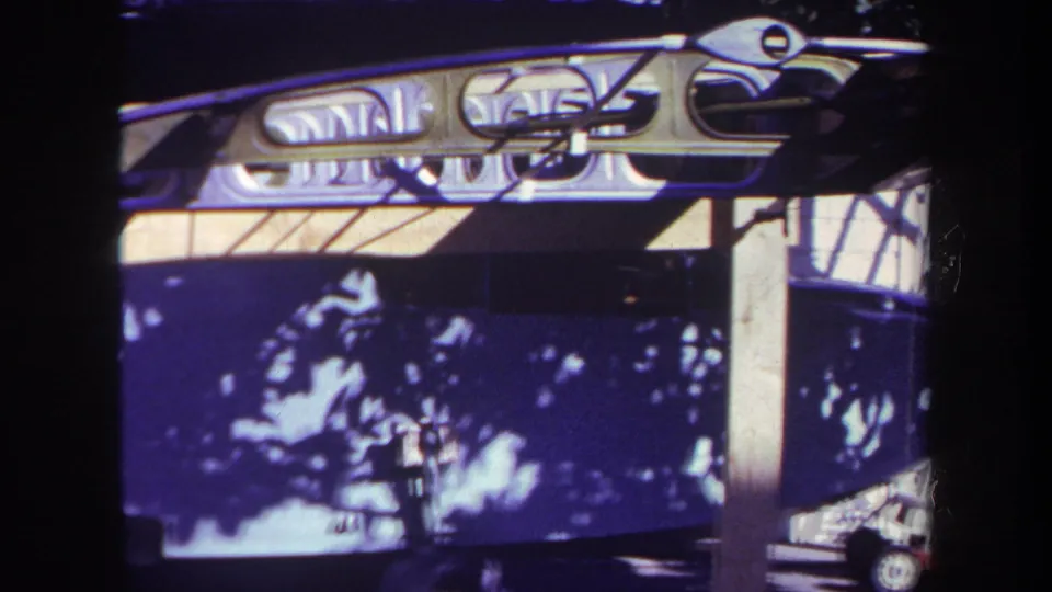 1969 Yucaipa-area home-movie frame showing a dark boat hull, pale metal framing, and shaded reflections near a dock.