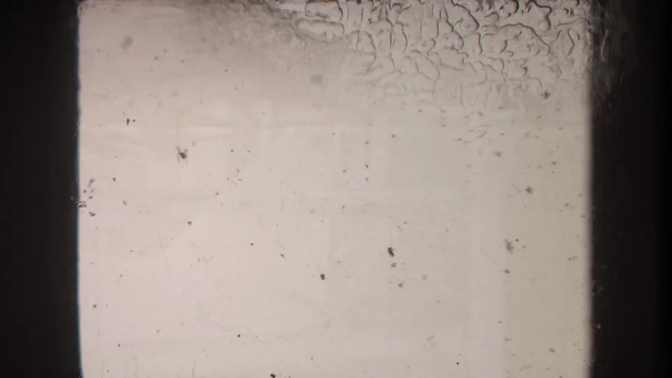 End frame from the 1969 8mm clip showing little subject detail, with pale exposure, dust, scratches, and visible film borders.