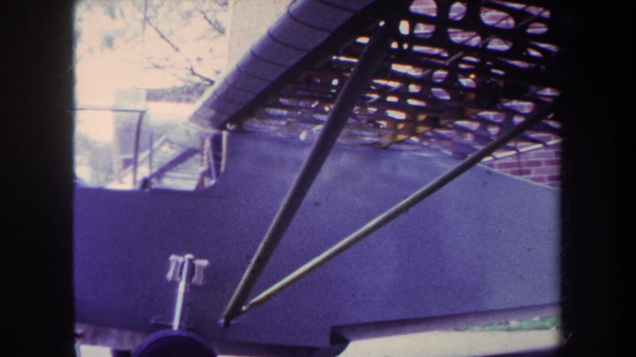 1969 Yucaipa home-movie frame showing a purple aircraft fuselage, open upper structure, metal struts, and front landing gear.