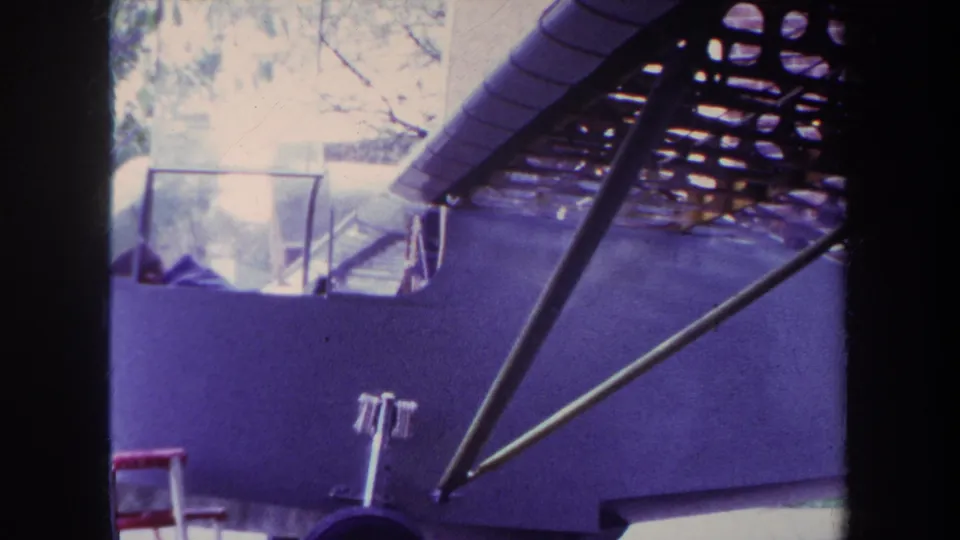 1969 Yucaipa frame of the custom airplane under construction, with side fuselage, cockpit opening, metal struts, and red ladder visible.