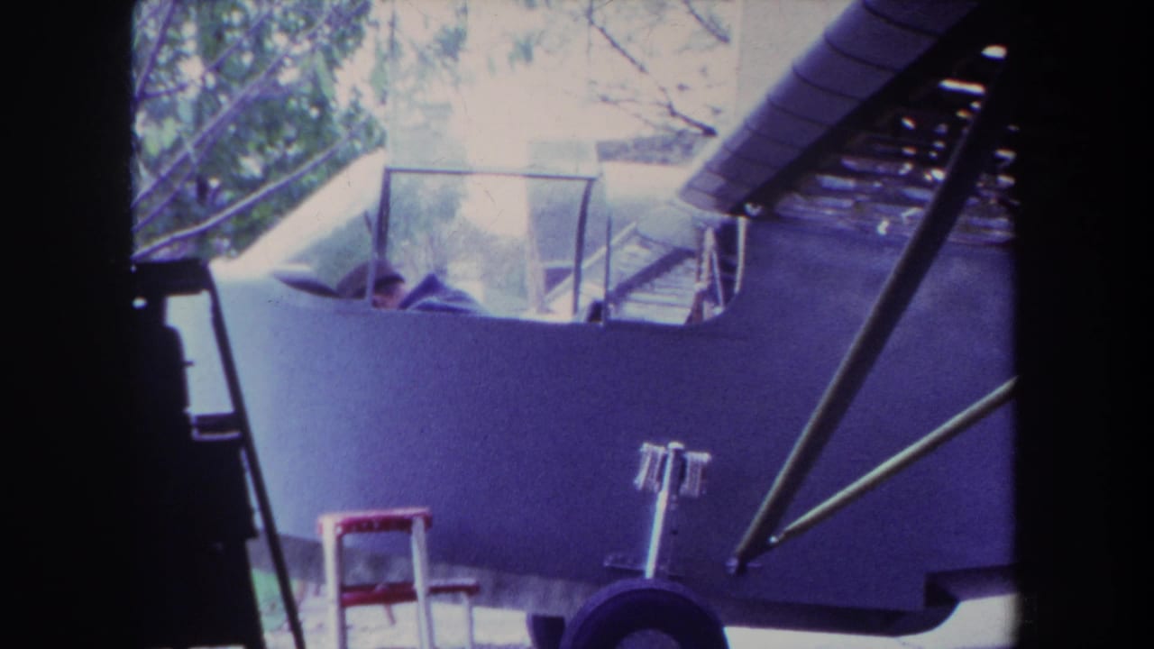1969 Yucaipa home-movie frame showing a pilot in a small light airplane cockpit, seen through dark film-edge framing.