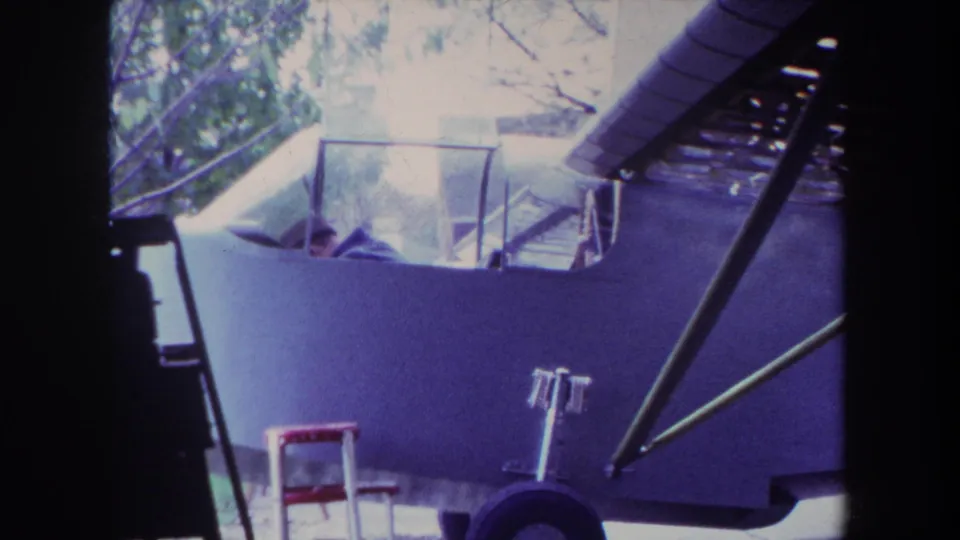 1969 Yucaipa home-movie frame showing a pilot in a small light airplane cockpit, seen through dark film-edge framing.