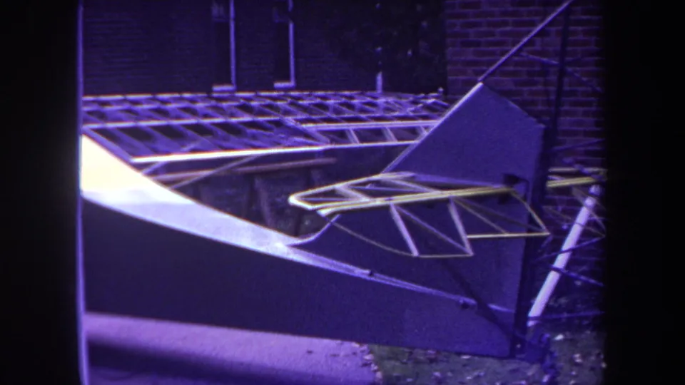 Final 1969 frame of the model airplane tail and elevator structure, filmed outdoors with visible 8mm grain and color shift.