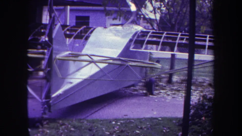 1969 Yucaipa frame of the homebuilt aircraft beside the driveway, with a small possible person or object near the right edge.