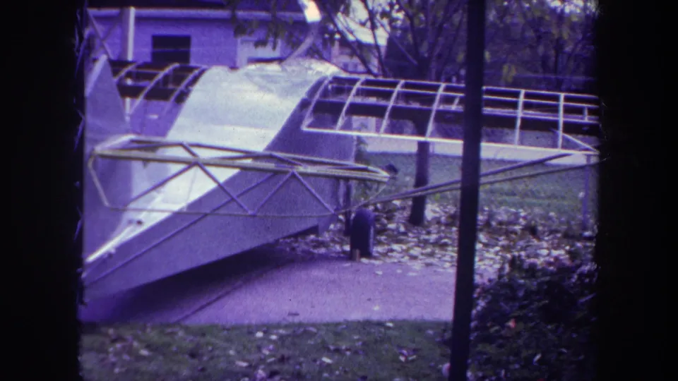 Purple-tinted 8mm view of a damaged aircraft fuselage and frame near trees in Yucaipa, California.