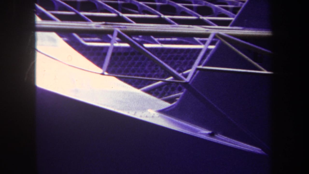 Curved roof framework with pale damaged panels and dark shadowed areas.
