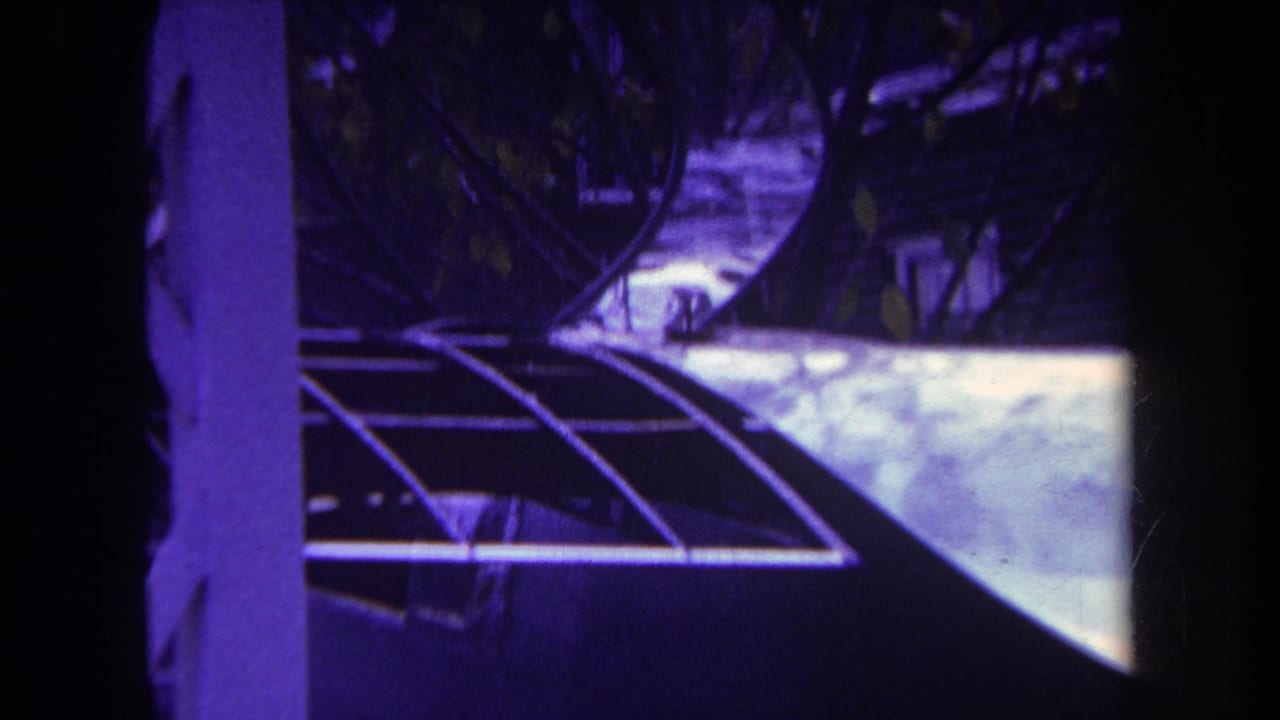 1969 Yucaipa home-movie frame showing an airplane tail near a house, partly blocked by dark foreground framing.