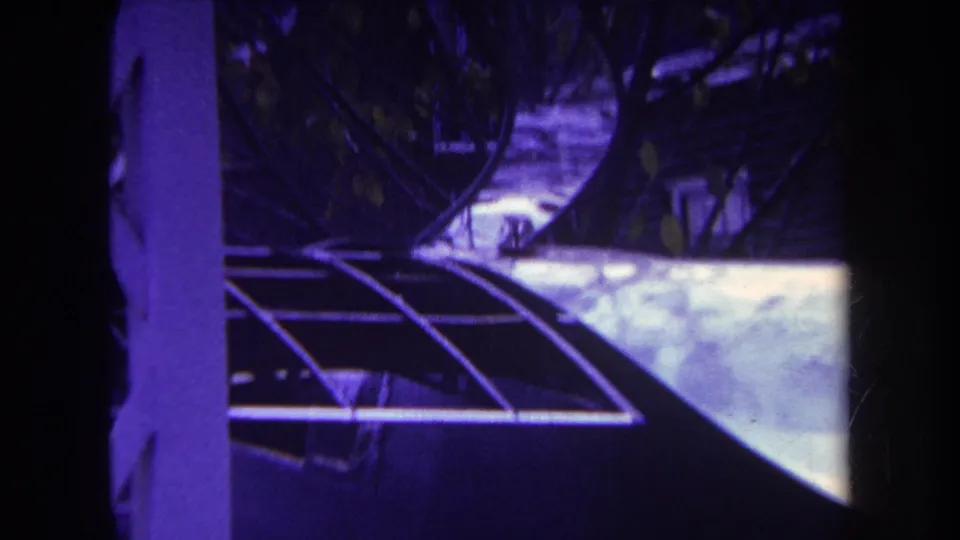 1969 Yucaipa home-movie frame showing an airplane tail near a house, partly blocked by dark foreground framing.