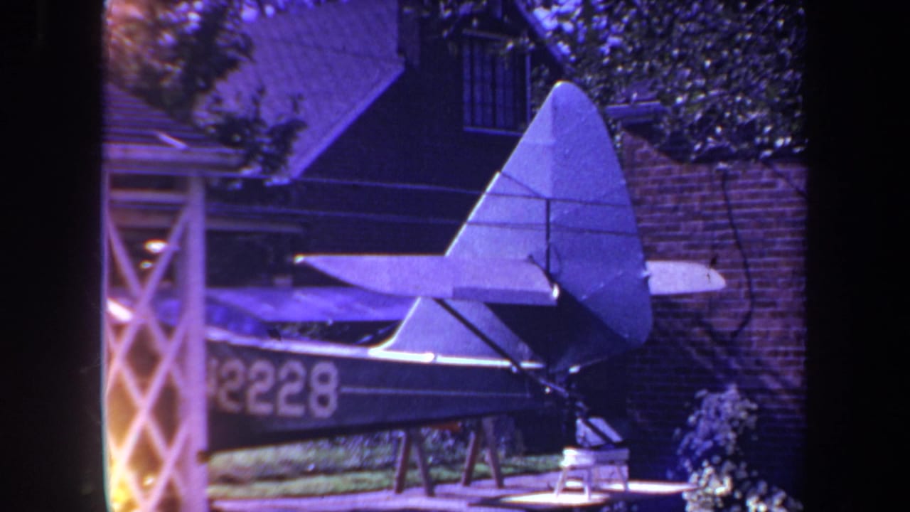 1969 Yucaipa home-movie frame showing the rear section of a homemade model airplane in a backyard setting.